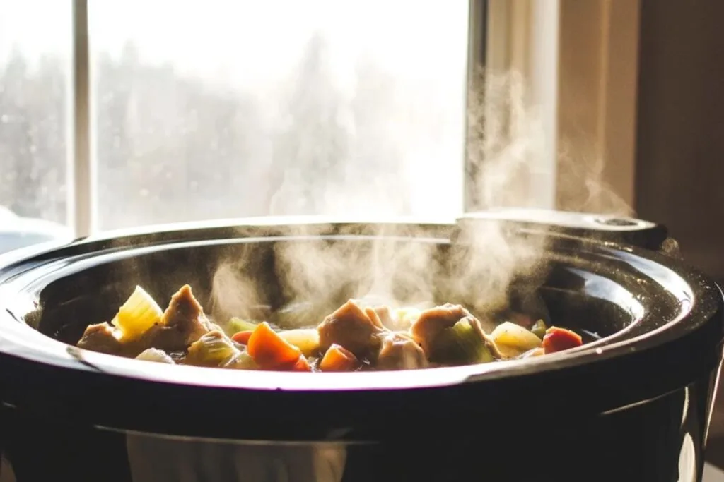 Frozen chicken cooking in a crockpot with vegetables
