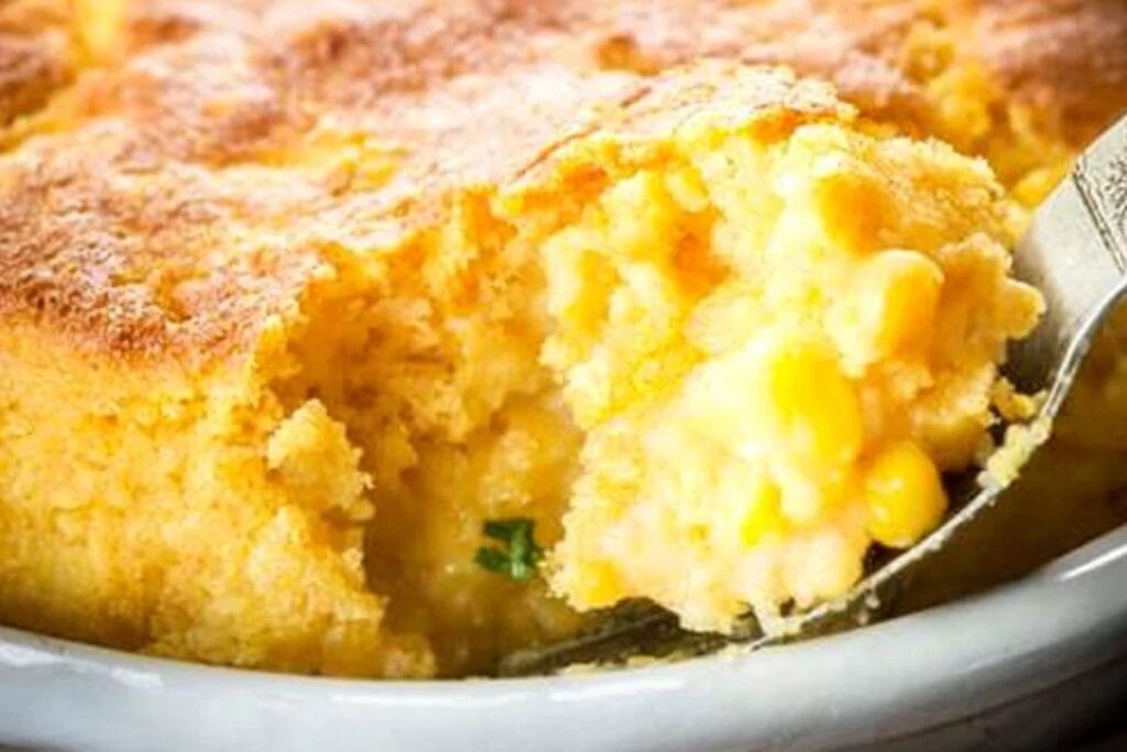 A golden-baked cornbread pudding served in a cast-iron skillet with a crispy top and creamy center.